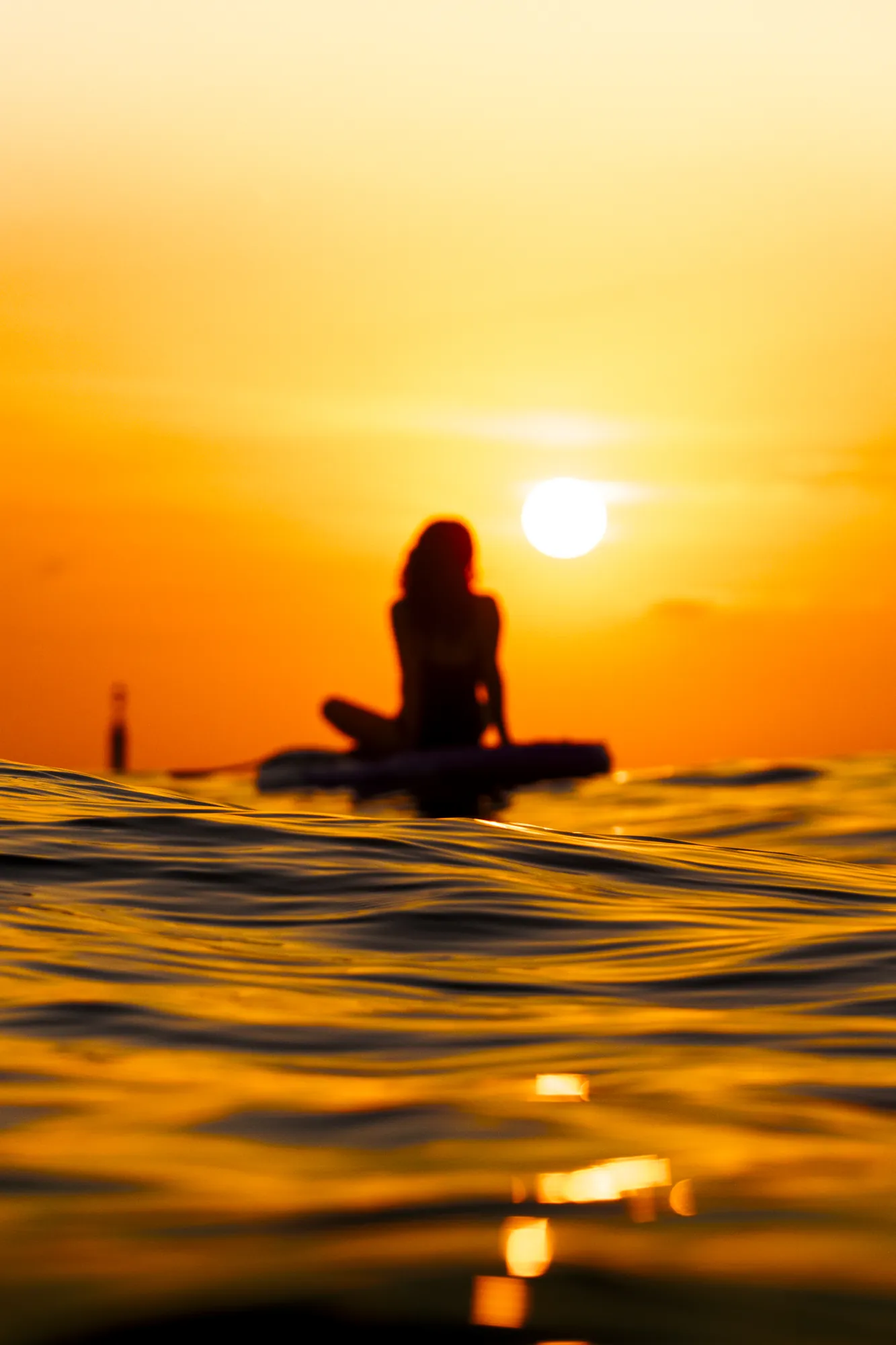 Woman on a paddle board at sunrise in Barcelona, water-level view